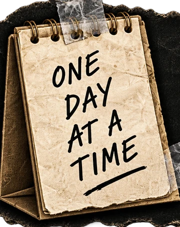A desk calendar reading: one day at a time